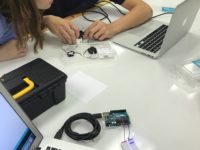 Students wiring an Arduino with one already set up with bulb it up in foreground